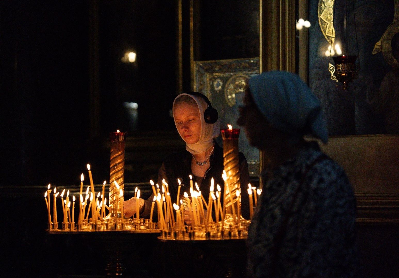 Menschen entzünden Kerzen in einer dunklen Kirche zur stillen Einkehr