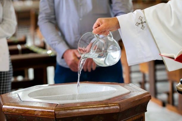 Geistlicher gießt Wasser über ein Taufbecken in einer Kirche